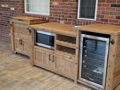 an outdoor kitchen with two ovens and cabinets on the side of the house, in front of a brick wall