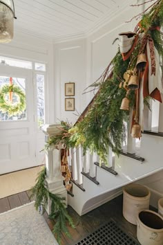 the stairs are decorated with evergreen and bells