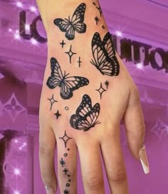 a woman's hand with butterflies on it and stars all over the wrist tattoo