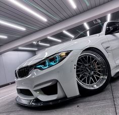 a white car parked in a parking garage next to a wall with lights on it