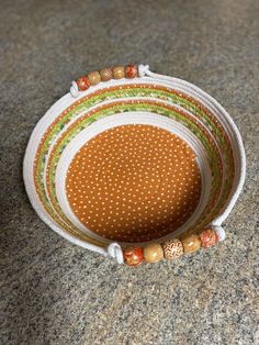 a brown and white bowl sitting on top of a counter next to a wooden beaded bracelet