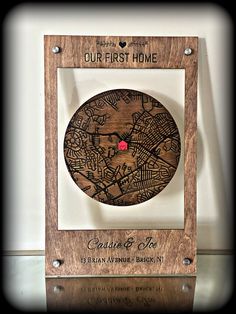 a wooden plaque with the words our first home on it and a red pin in the middle