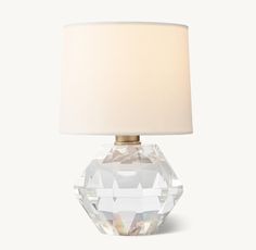 a clear glass table lamp with a white shade