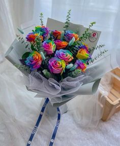 a bouquet of multicolored roses is wrapped in white paper and tied to a blue ribbon