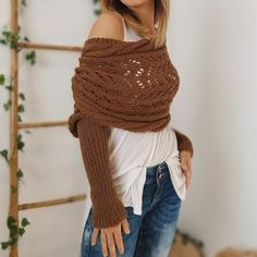 a woman wearing a brown knitted wrap around her shoulders and arms, posing for the camera