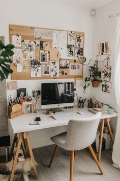 a white desk topped with a computer monitor next to a chair and potted plant