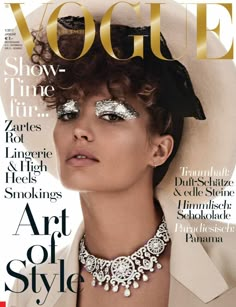 a woman with silver makeup on the cover of a magazine, wearing a white hat