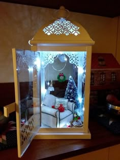 a christmas display in a glass case with lights on the top and furniture below it