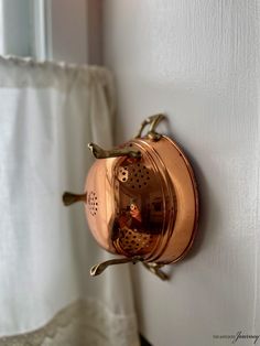 a metal clock mounted to the side of a white wall next to a shower curtain