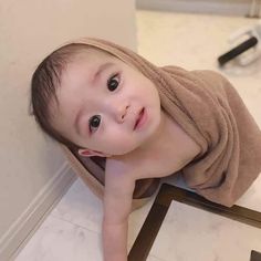 a baby wrapped in a towel sitting on the floor