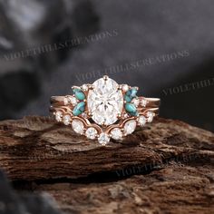 a diamond and turquoise stone ring sitting on top of a piece of wood next to rocks