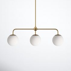 three white balls are hanging from a brass chandelier