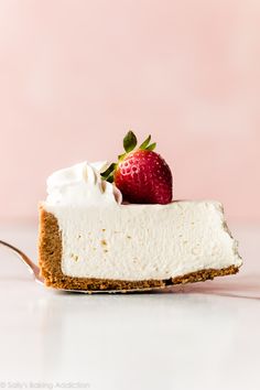 a slice of cheesecake topped with whipped cream and a strawberries on top, sitting on a pink surface