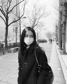 a woman wearing a face mask while walking down the street with her hand in her pocket