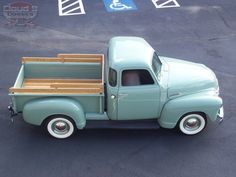 an old green truck parked in a parking lot