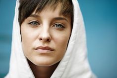 a woman wearing a white hoodie looking at the camera with a serious look on her face