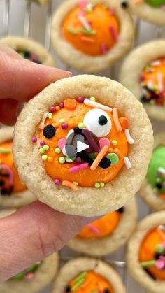 a person holding up a cookie decorated like a monster with sprinkles on it