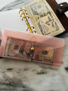 a note book and money are sitting on a marble counter top next to a wallet