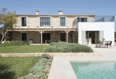 a house with a pool in front of it and an outdoor dining area on the other side