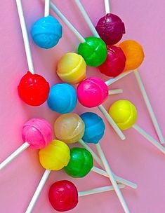 colorful lollipops on a pink background with white and yellow sticks in the middle