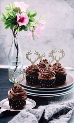 cupcakes with chocolate frosting and deer antlers on top are sitting on a plate