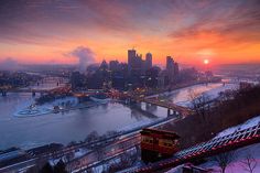 the sun sets over a city and river