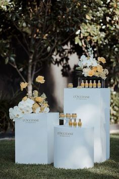 three white bags with yellow and white flowers on them sitting in the grass next to each other