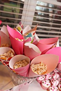 a vase filled with lots of pink cupcakes and muffins on top of a table