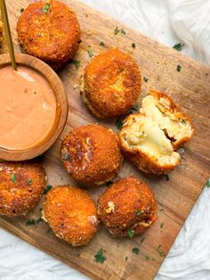 some food is laying on a cutting board with a bowl of dipping sauce next to it