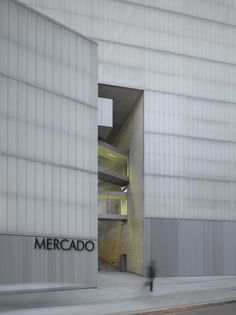 a man walking past a tall building with a sign on it's side that says mercado