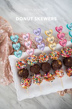 chocolate covered donuts with colorful sprinkles on a white plate next to pink and gold sequins