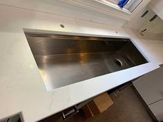 a stainless steel sink in the middle of a white counter top with a skylight above it