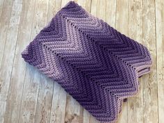 a crocheted blanket laying on top of a wooden floor