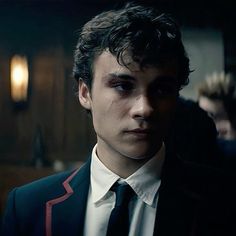 a young man in a suit and tie looking at the camera with an intense look on his face