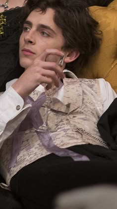 a young man sitting on top of a couch holding a wine glass in his hand