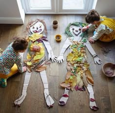 two children are making scarecrows out of paper plates and newspaper strips on the floor