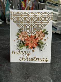 a christmas card with poinsettis and pine cones on it sitting on a table