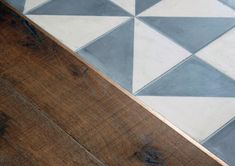 a wooden floor with white and grey tiles on it's sides, next to a wood floor