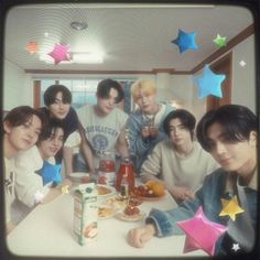 a group of young men sitting around a table with food and drinks in front of them