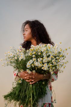 a woman holding a bunch of flowers in her hands