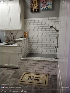 a white tiled bathroom with a dog door mat and rug on the floor next to it