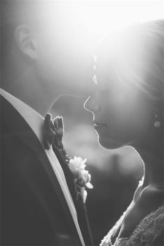 black and white photograph of a bride and groom looking at each other with the sun shining behind them