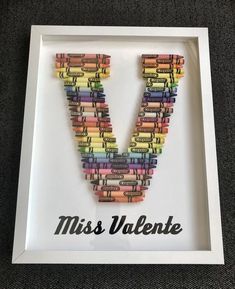 the letter v made out of crayons is displayed in a white frame