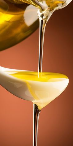 oil being poured onto a spoon with liquid pouring from it into the bowl and on top