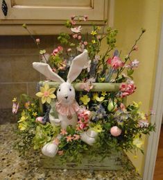 a basket filled with flowers and a stuffed bunny sitting on top of a kitchen counter