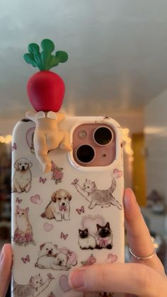 a person holding up a phone case with dogs and cats on it in front of an apple