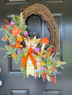 a wreath on the front door with an orange bow and mushroom decorations hanging from it