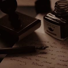 a pen and ink bottle sitting on top of a desk next to a notepad