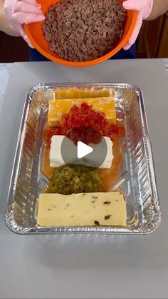 a person in pink gloves holding a bowl with food on it and an orange plate