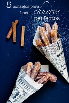 two cones of doughnuts sitting on top of a blue table next to cinnamon sticks